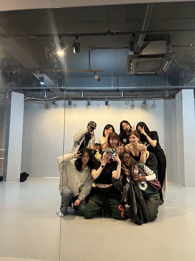 a group of girls taking a mirror selfie in a dance practice room