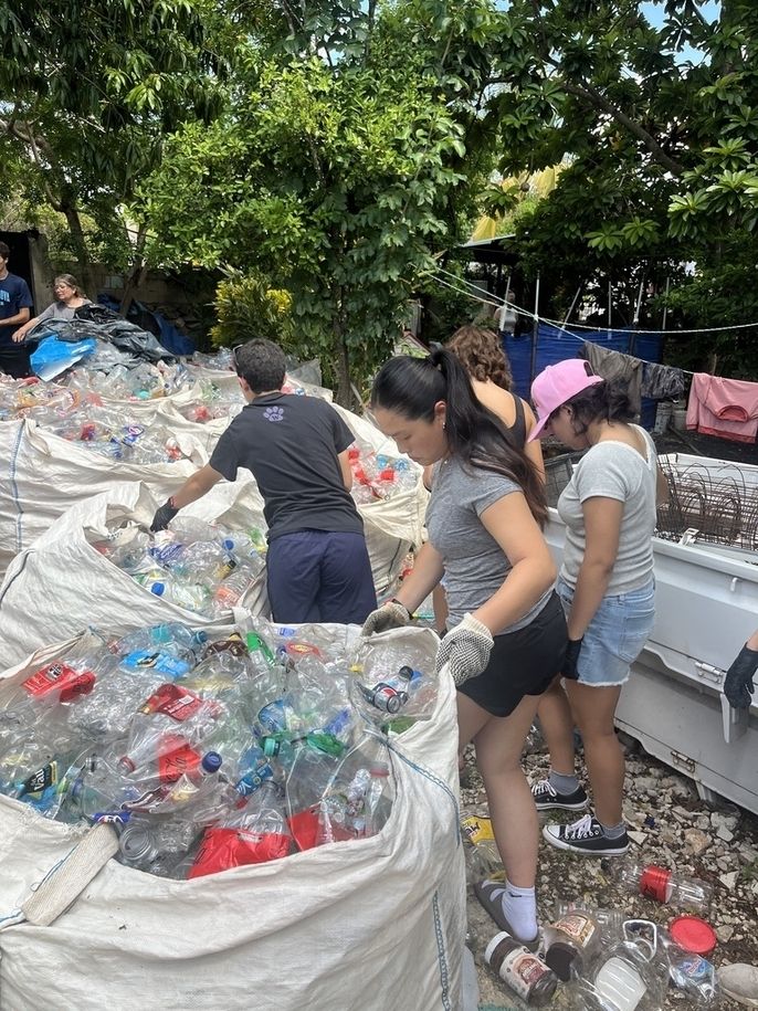 Students sort recycled bottles while volunteering at Zarigüeyas