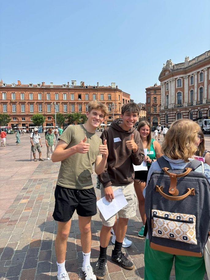 Two students smiling and giving a thumbs up