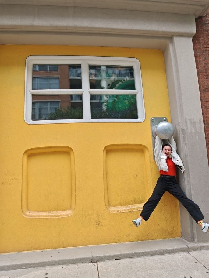 Alizée hangs from the doorknob of the well-known giant yellow door at Big Monster Toys in Chicago.