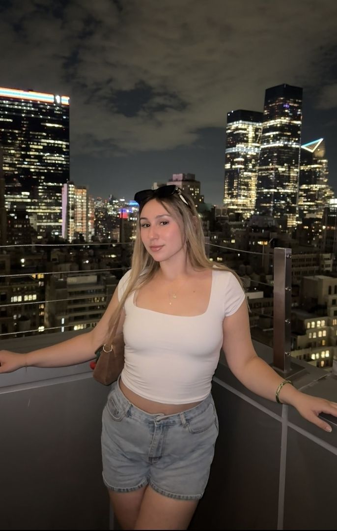 woman posing in front of new york city skyline at night