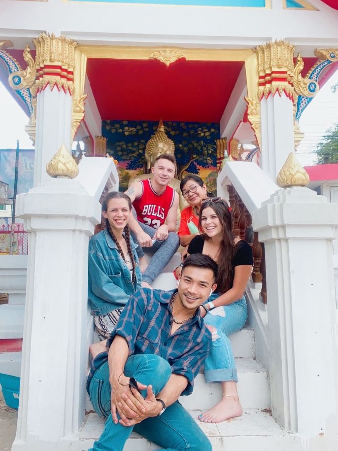 Young people sitting on the steps of a temple in Thailand