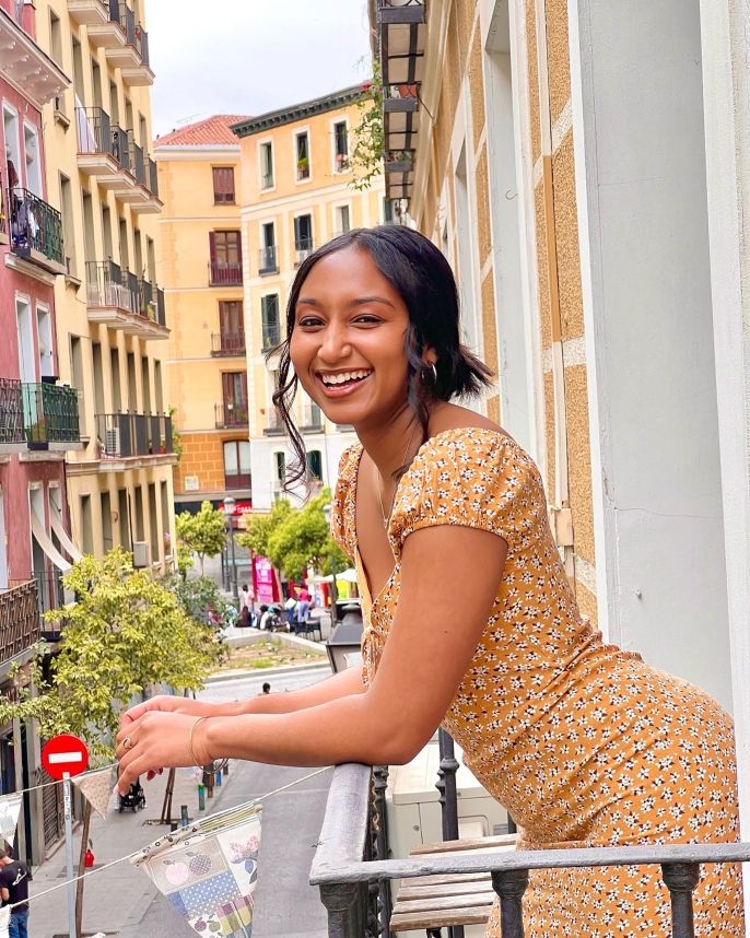 Young woman in yellow dress smiling on balcony