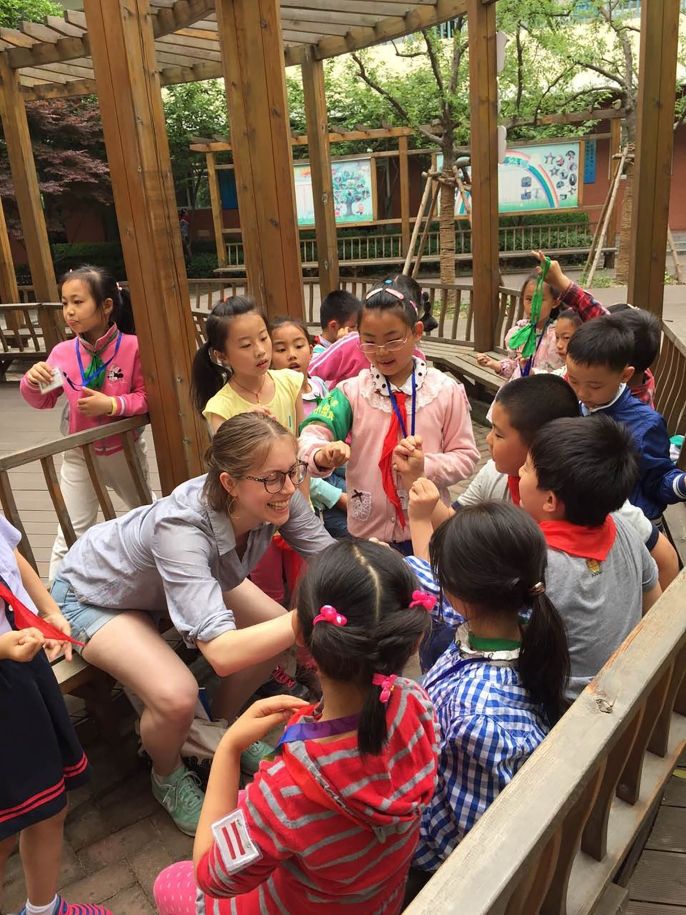 Teacher kneeling outside with students in China