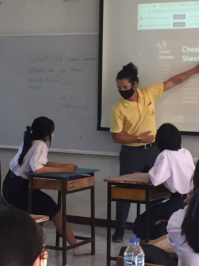 TEFL teacher pointing at projector in classroom