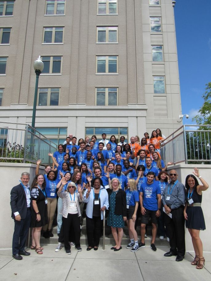 A group of students standing on stairs in blue CIEE T-shirts with CEO Jim Pellow at the Civic Leadership Summit