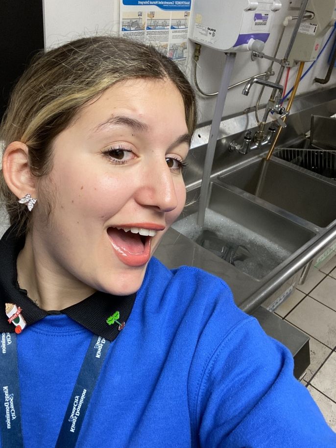 A selfie of Eleni in front of a silver sink in an industrial kitchen