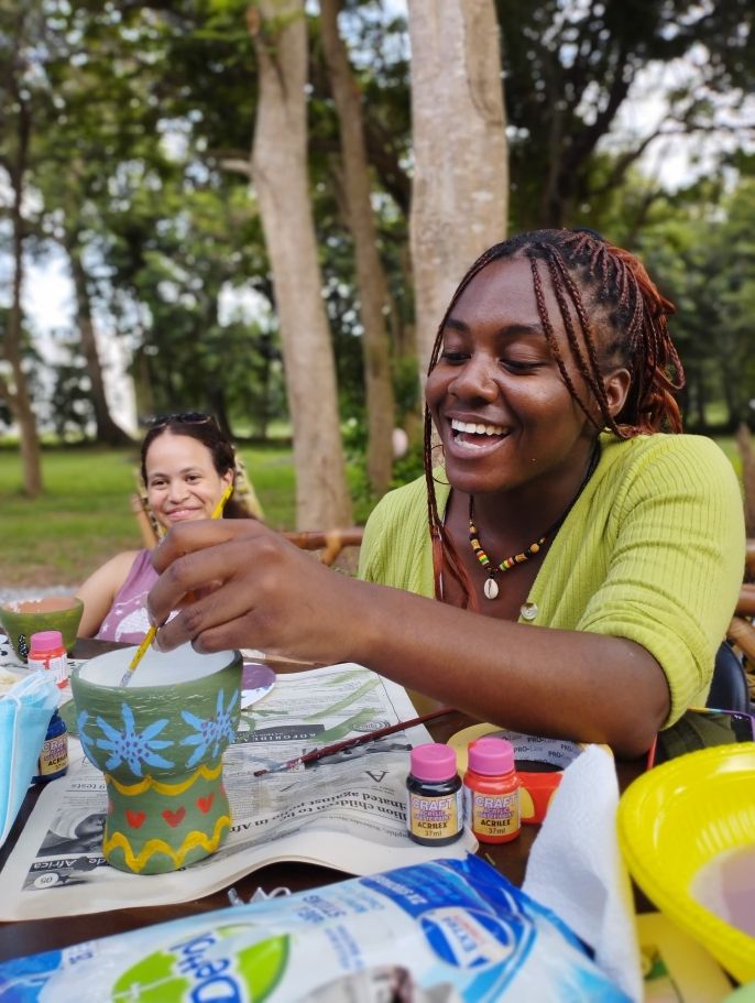 legon student painting a flower pot outside