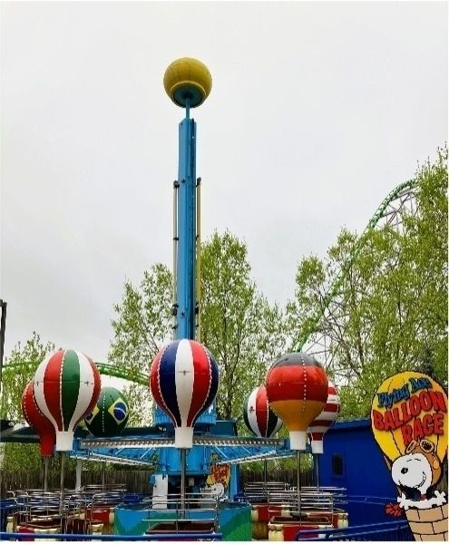 a ride in an amusement park with mini-hot air balloons that display flags of different colors