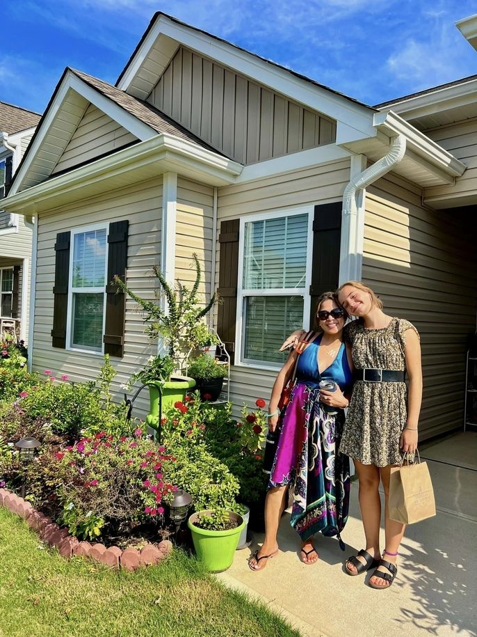 A host mom and daughter pose in front of their house.