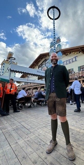 a man in traditional german clothes stands in a town square