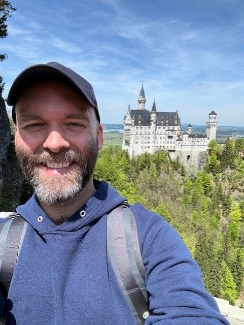 a selfie of a man in front of a german gothic castle