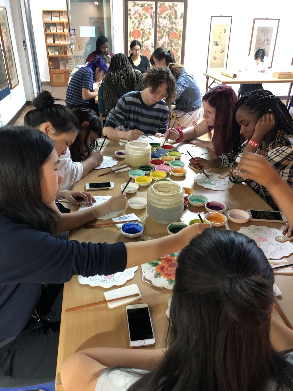 Students painting a Korean folk drawing on a fan made out of Korean traditional paper, Hanji