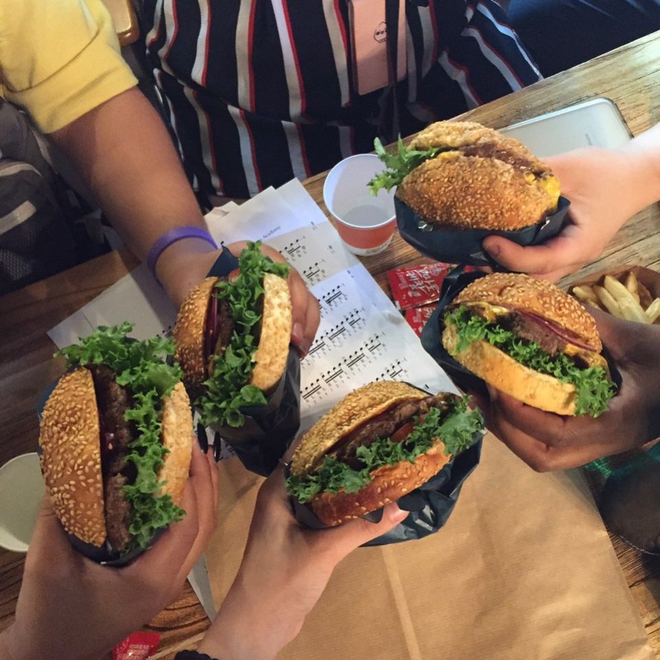 Several people holding hamburgers. 