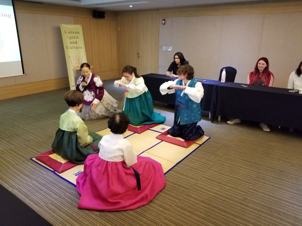 American high school students learning to bow and pay respects to elders while dressed in Korean traditional garb.
