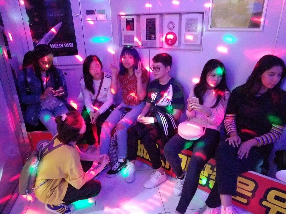 Students sitting in a Karaoke room with bright lights flashing.