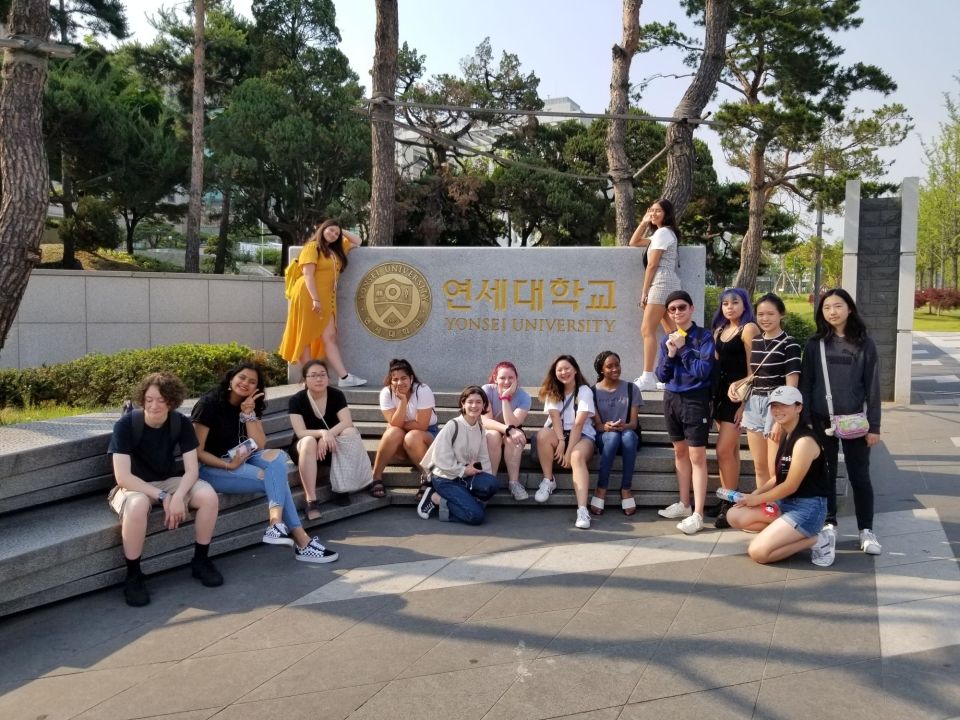 Students posing in front of Yonsei University's campus by the university sign
