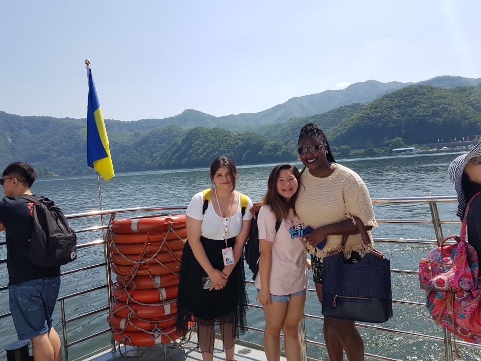 Two students posing for a photo with a Program Leader while riding a ferry to Nami Island.