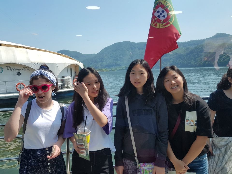 Four students posing for a photo while riding a ferry to Nami Island.