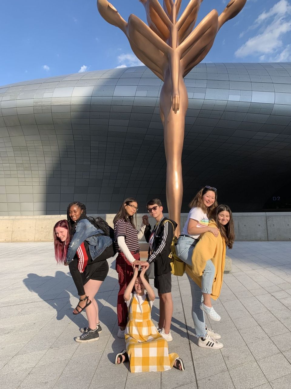 Students replicating a statue in front of Dongdaemun Design Plaza. 