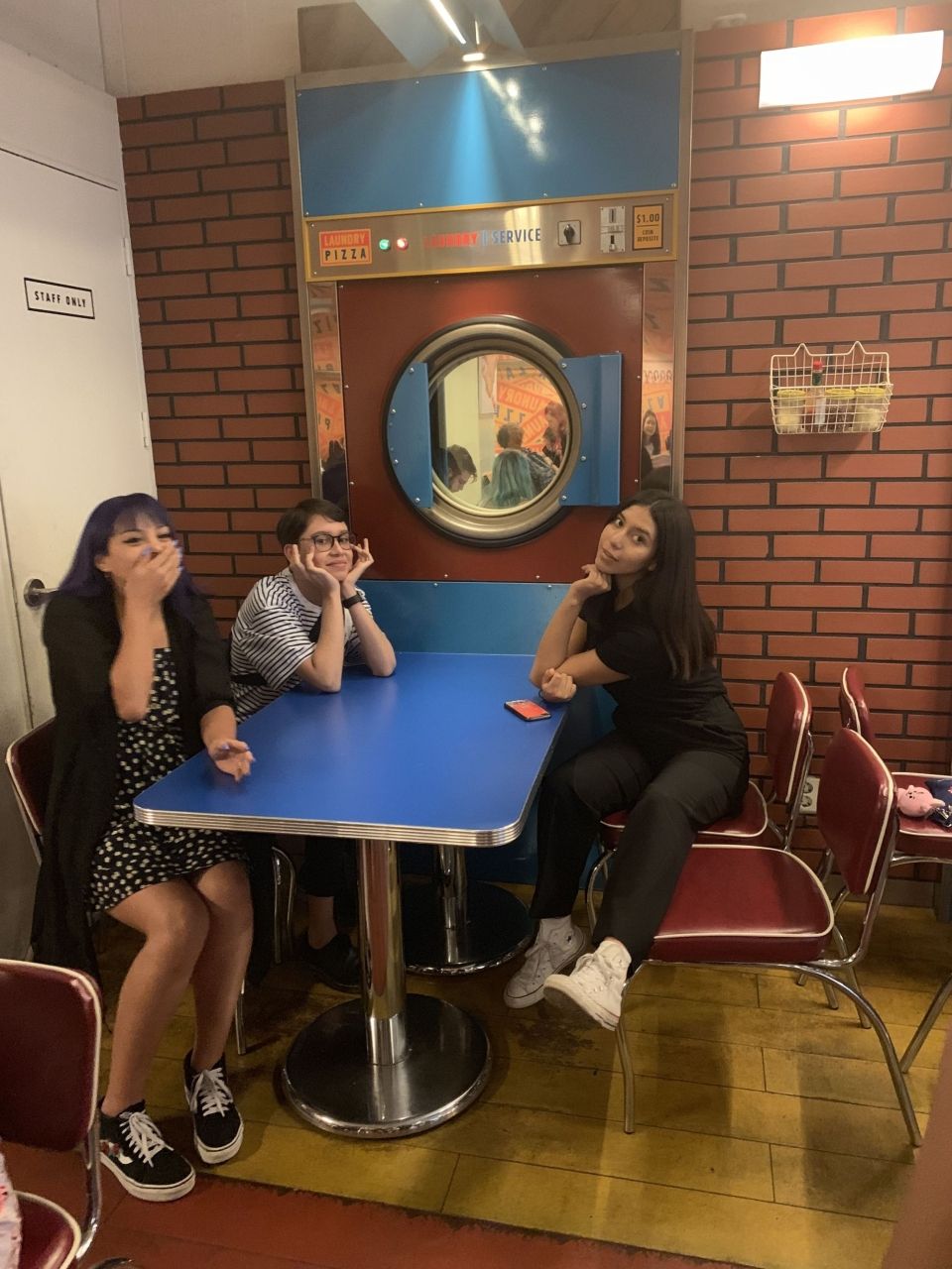Three students posing by the interior of Laundry Pizza restaurant.
