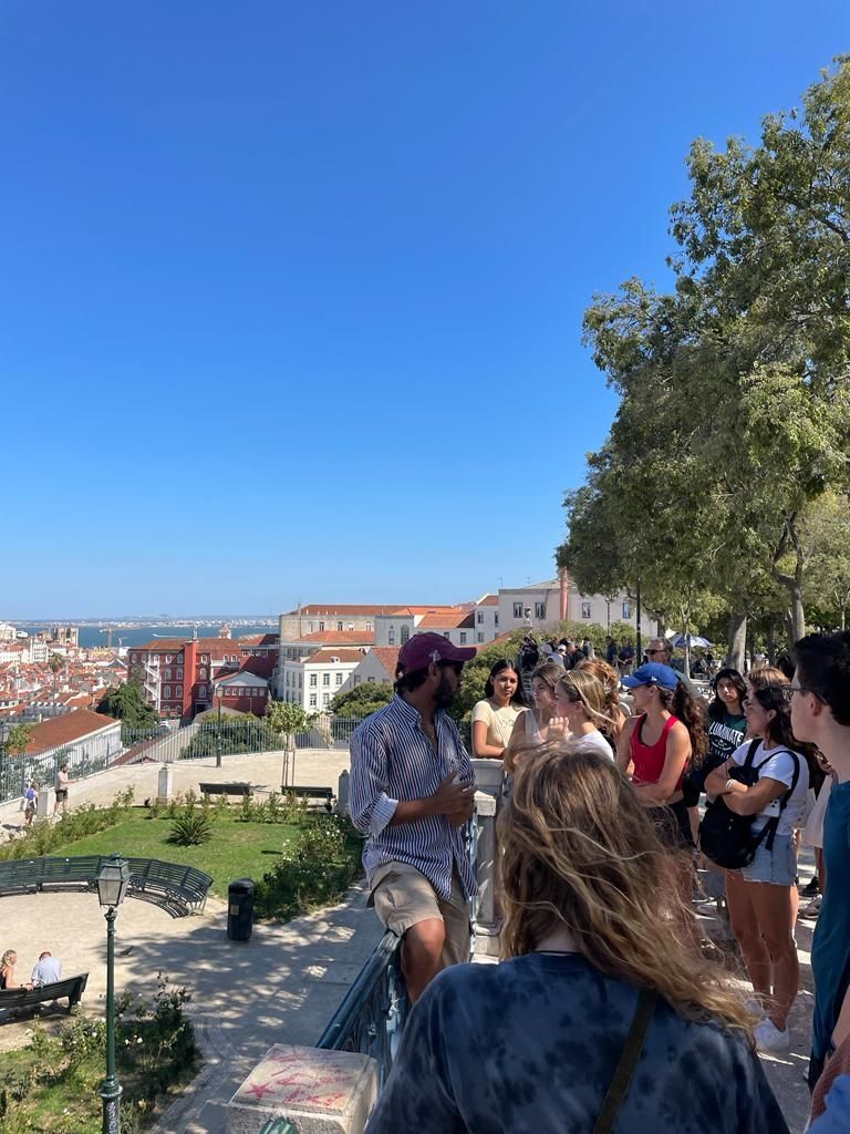 Group of students at vista of Lisboa during city walk. Castle can be seen in the background on the right.