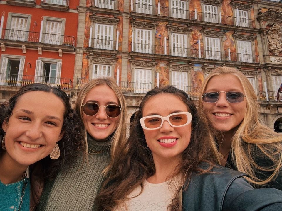 Four young women smiling in Plaza Mayor, Madrid, Spain