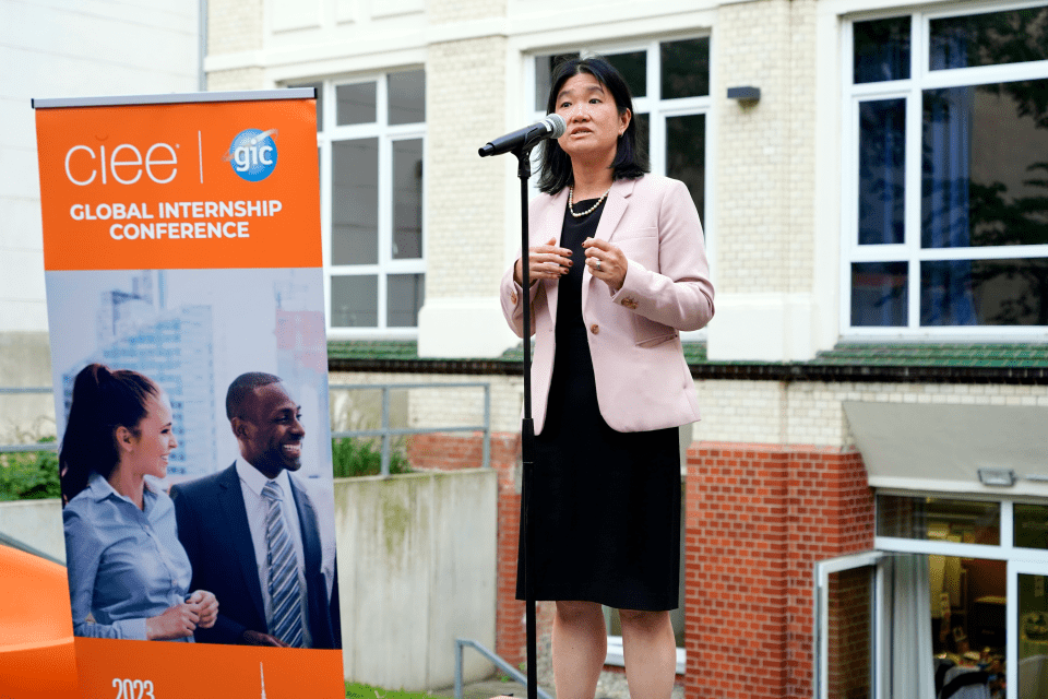 CIEE staff member speaking at a microphone in front of a banner that says "Global Internship Conference"