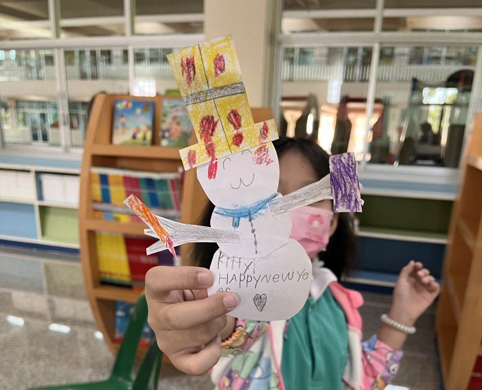 Child holds a paper snowman in a library
