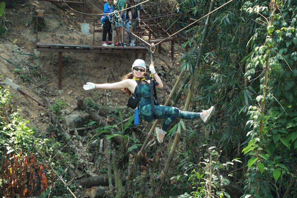 a young woman in a green tie-dye outfit poses as she zips down a zipline