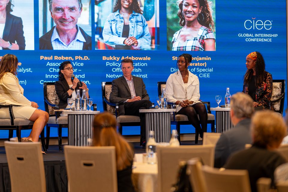a group of people sitting on stage talking on a panel