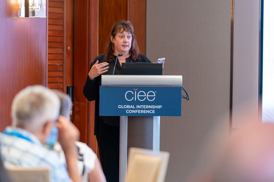 a woman at a podium speaking to a crowd