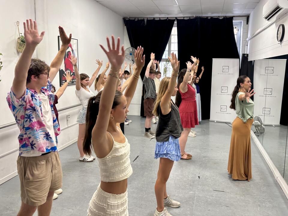 Students with their arms stright up to the ceiling with their hands twisted outward