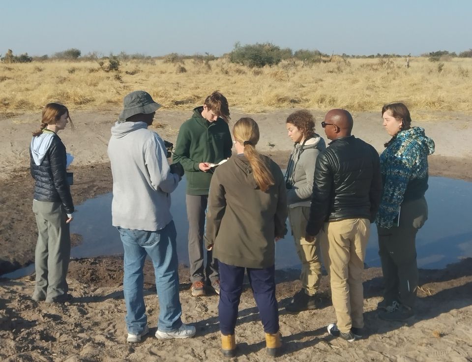 Professor Mahupeleng (second from left) and Dr. G. (second from right) instructing my peers in the use of camera traps near the Tsau waterhole in the CKGR