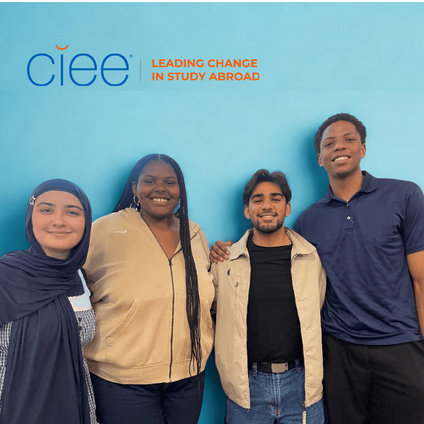 4 students stand in front of a bright teal wall, above it is a ciee logo and 'leading change in study abroad'