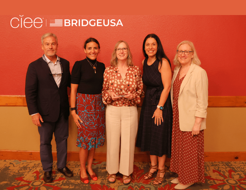 Tara Hensley holds an award while posing with four CIEE and BridgeUSA representatives at an awards event.