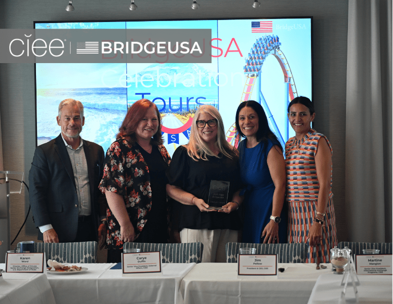 CIEE and BridgeUSA representatives pose with a woman holding an award during a BridgeUSA Celebration Tour event.