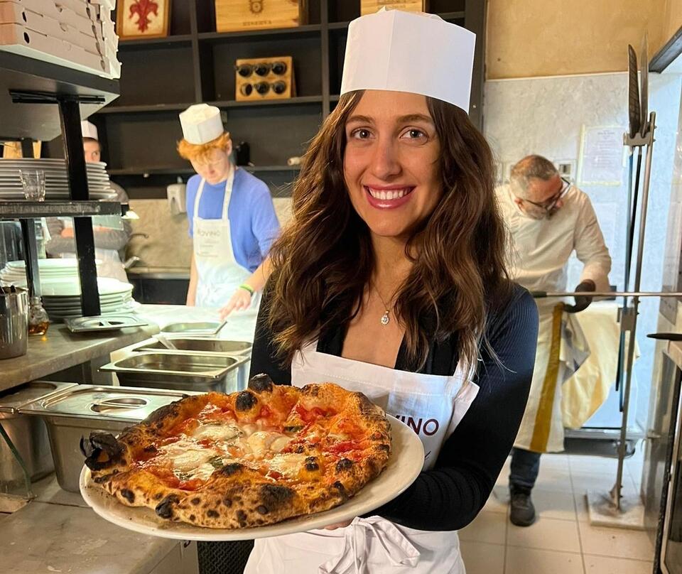 Spring 23 student holding the pizza she just made during a pizza making class in Florence