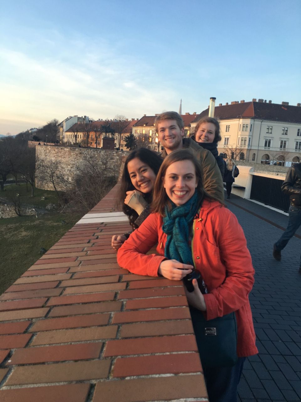 Young people smiling while leaning on brick wall in Budapest