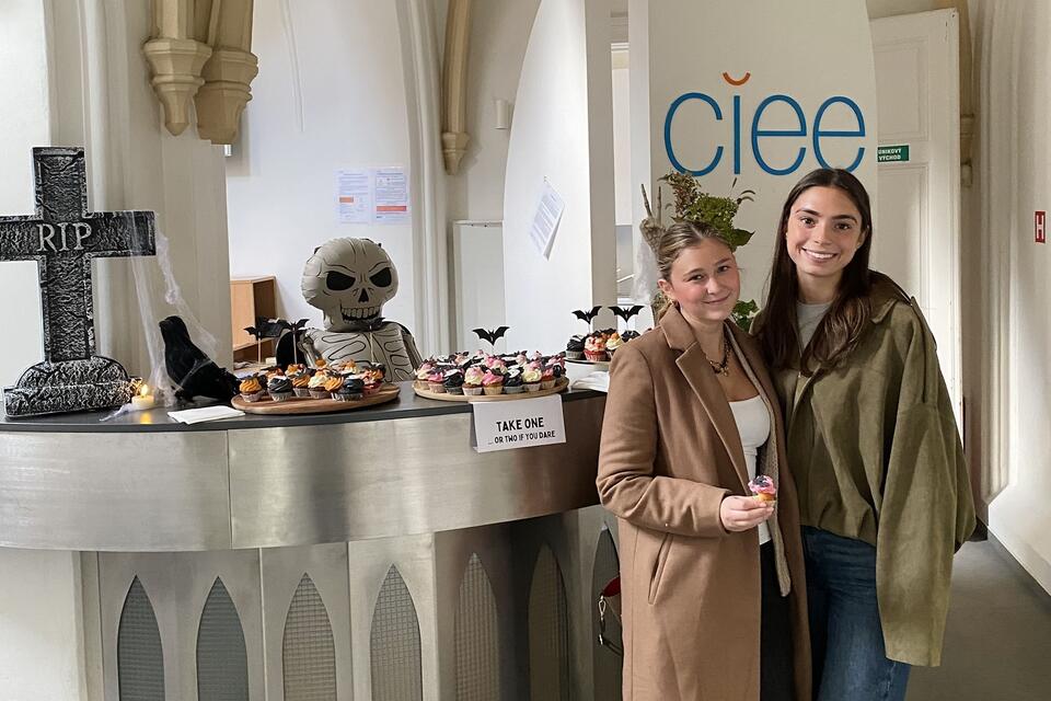 Female students posing next to the Halloween set up at CIEE Prague